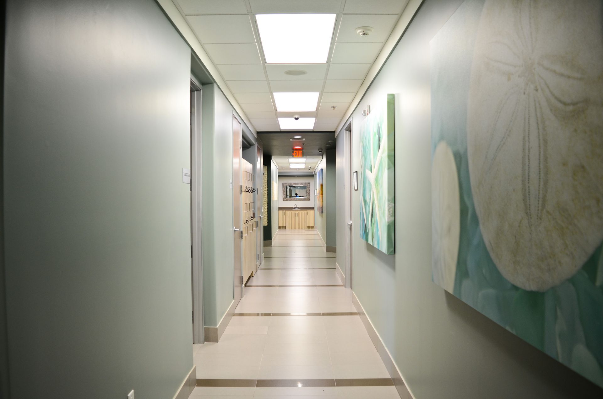 Long hallway with grey walls, recessed lights, and artwork.