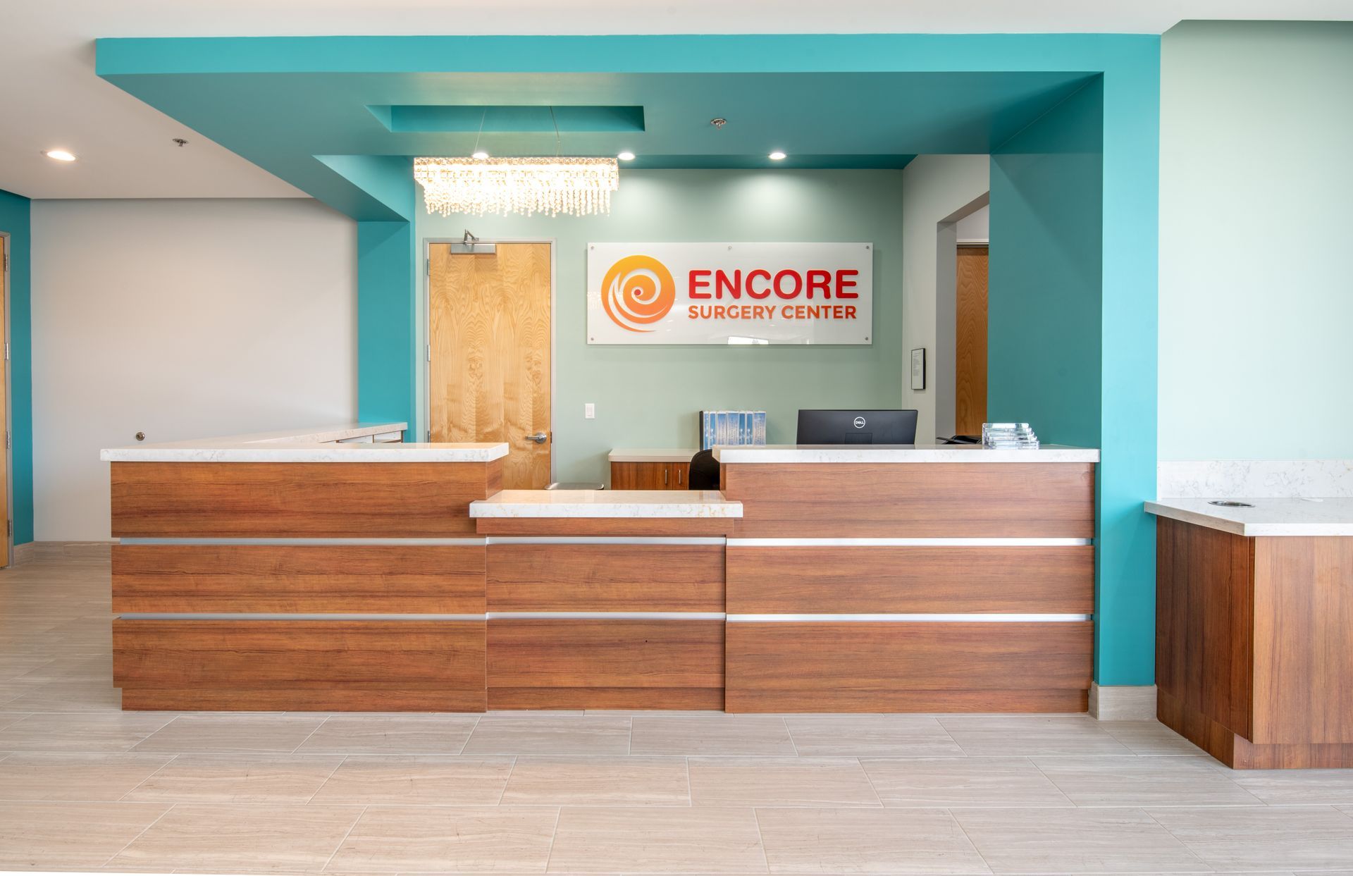 Reception area of Encore Recovery Center, teal walls and a wood-toned reception desk.