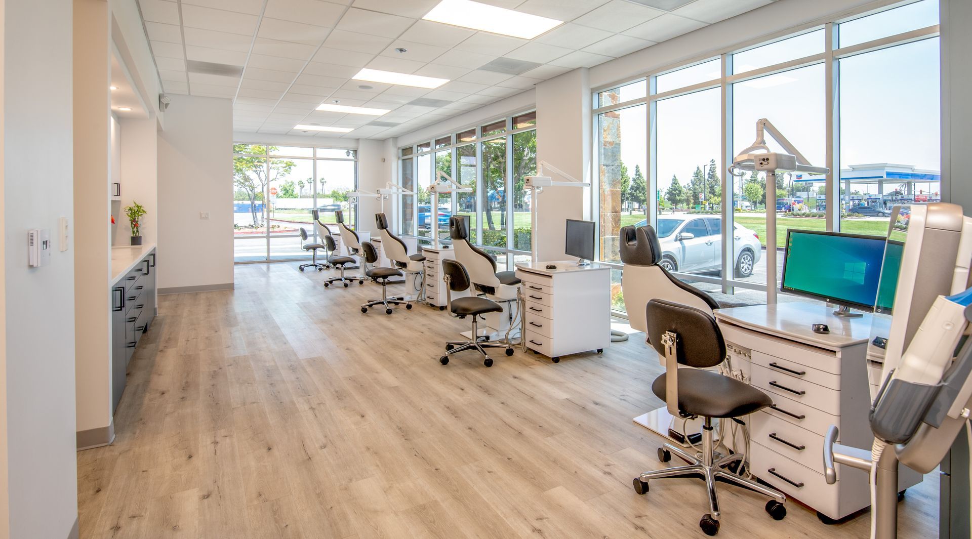 Modern dental office interior with treatment chairs, large windows, and light wood flooring.