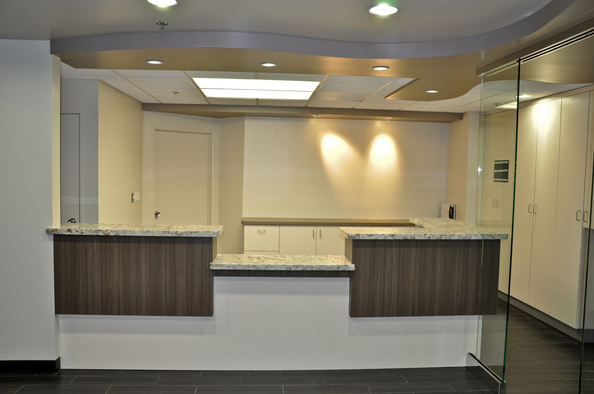 Reception desk with granite countertop and dark wood cabinetry.