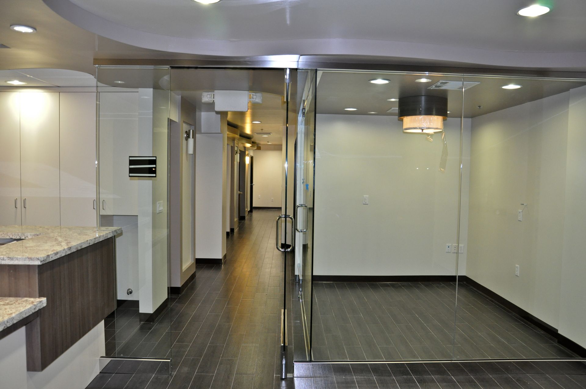 An interior view of a commercial space with a glass door, long hallway, and white walls.