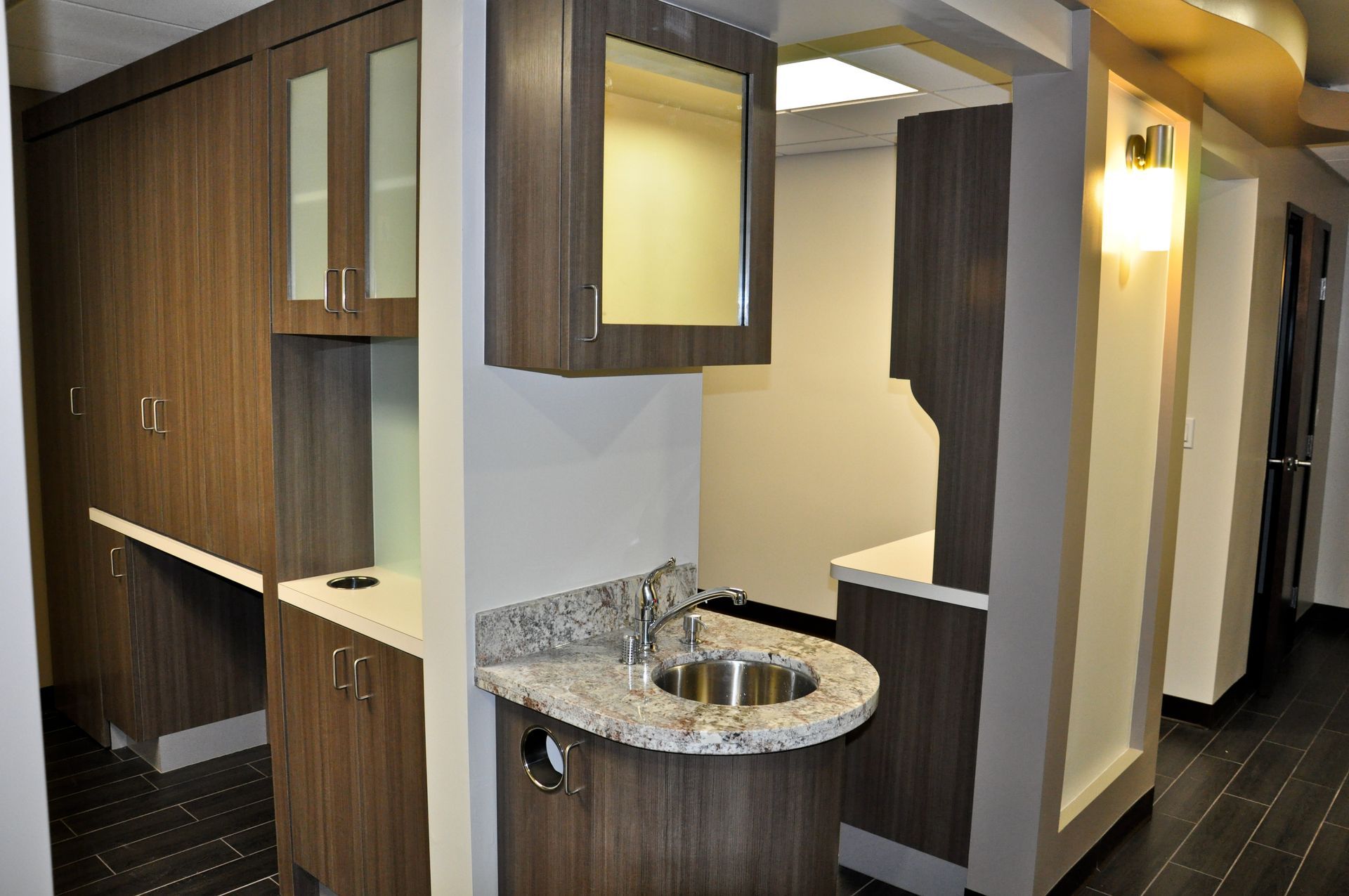 Dental office with dark wood cabinets, sink, and mirror.