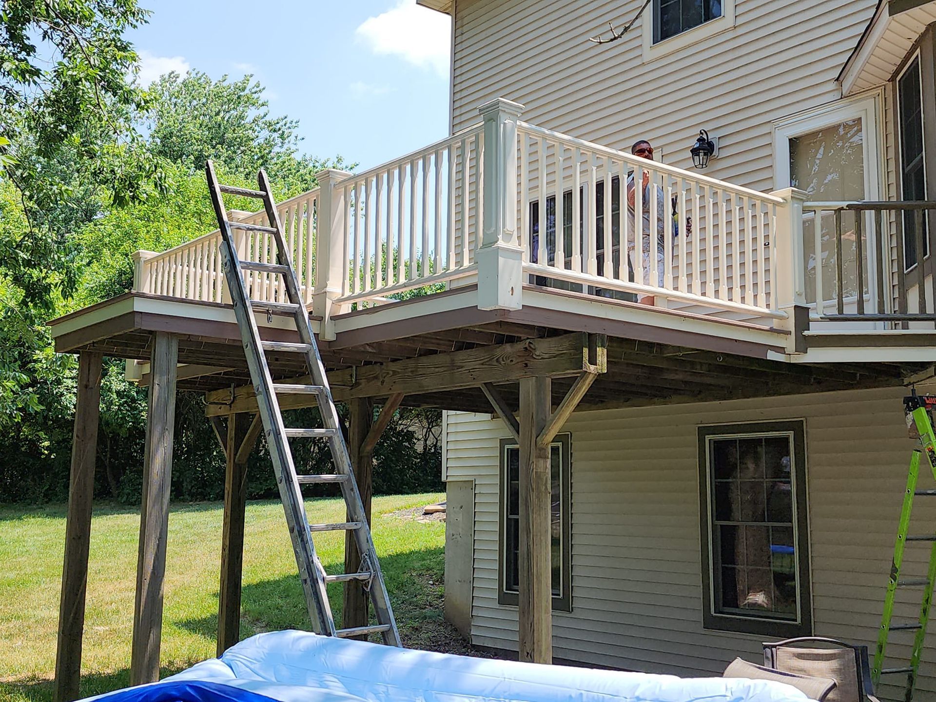 A house with a large deck and a ladder in front of it.