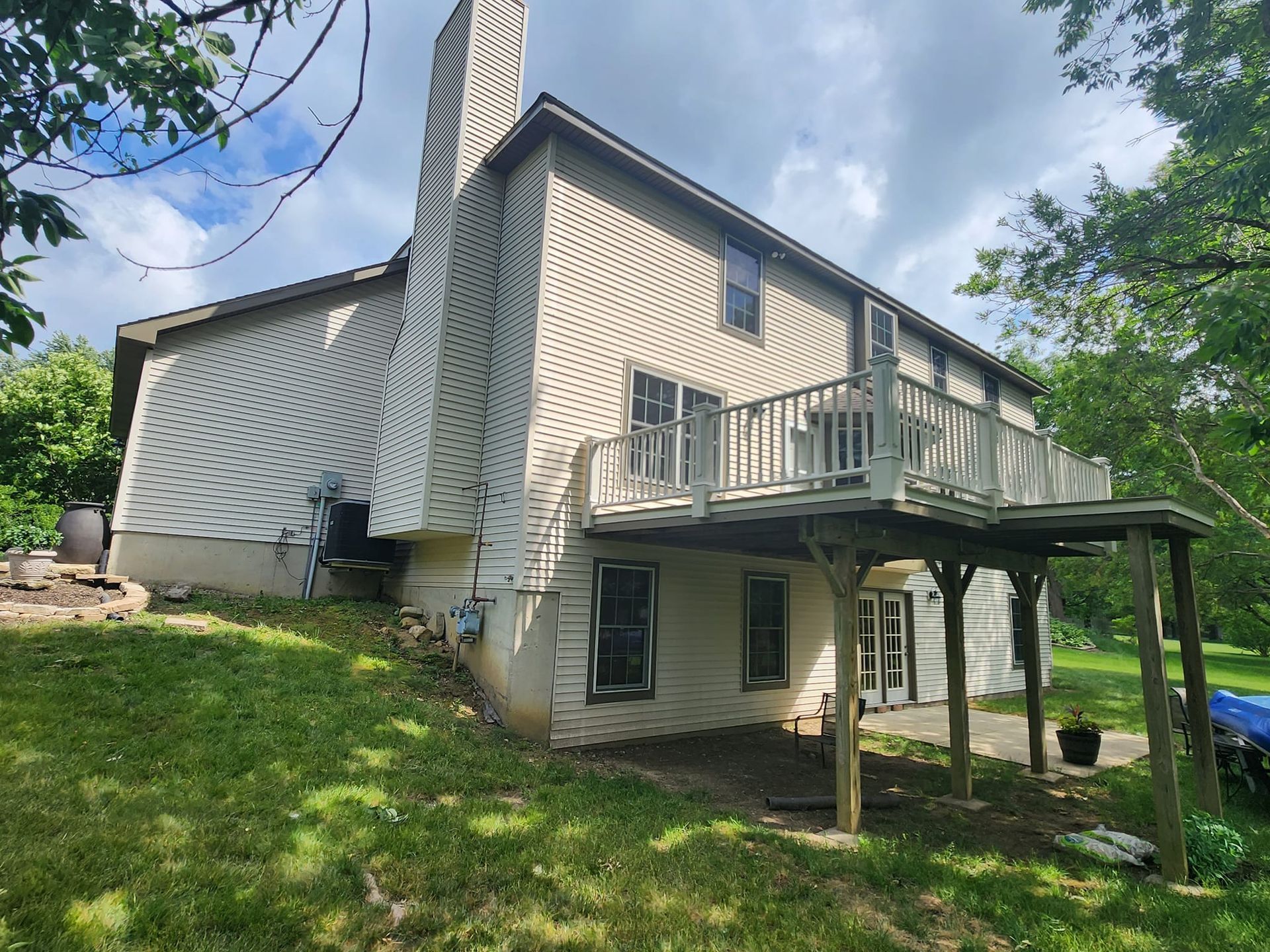 The back of a house with a large deck and a chimney.