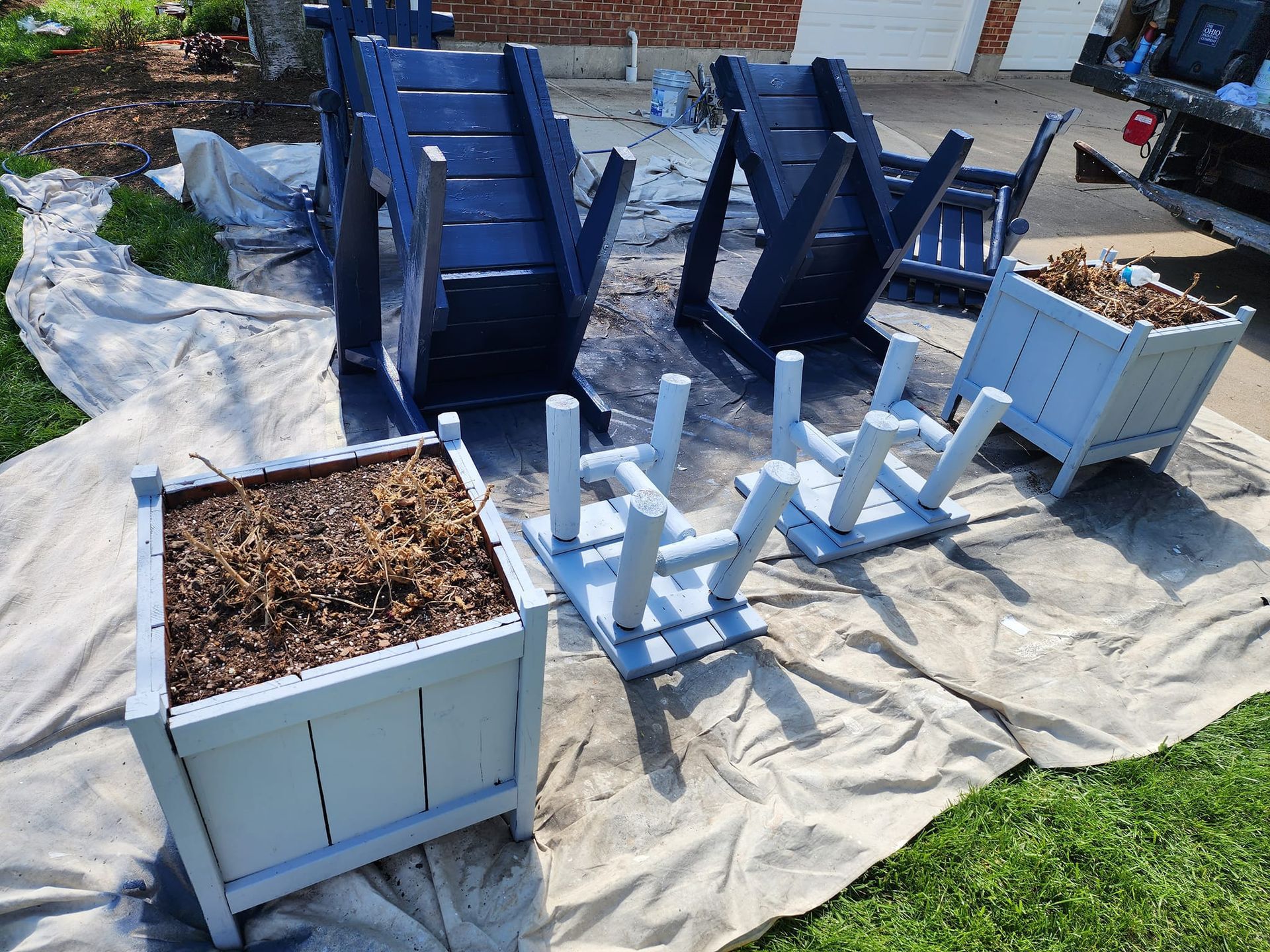 A group of chairs and planters are sitting on a tarp on the grass.