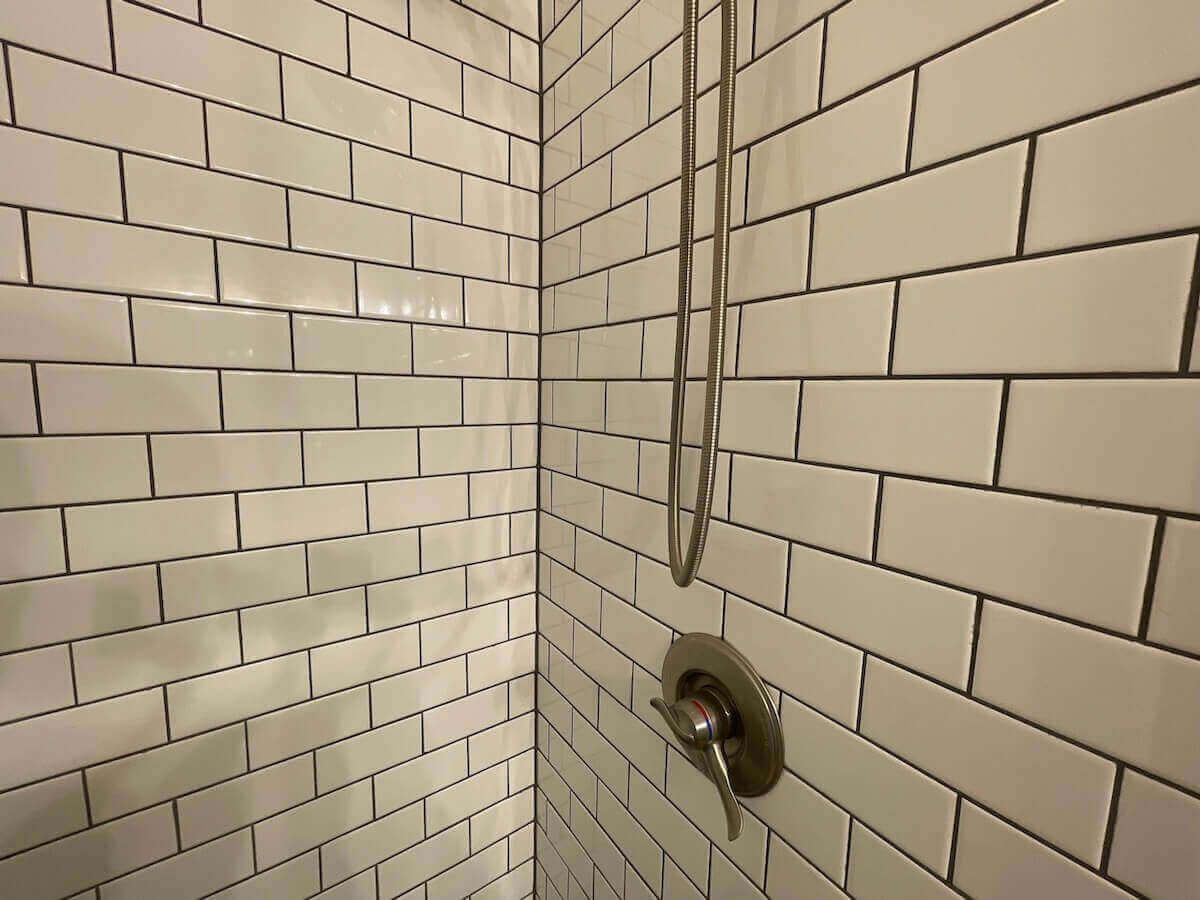 White subway tile shower with silver fixtures, corner view.