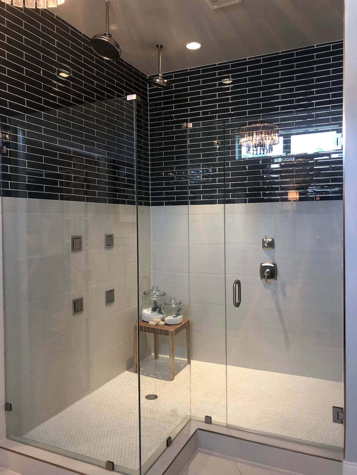 Modern shower with black and white tiled walls and glass doors.