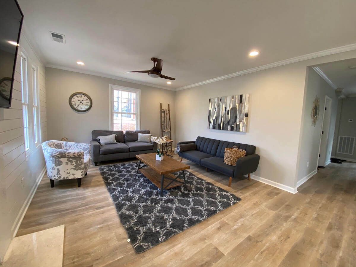 Living room with gray walls, wood floors, and furniture including a sofa, coffee table, and area rug.