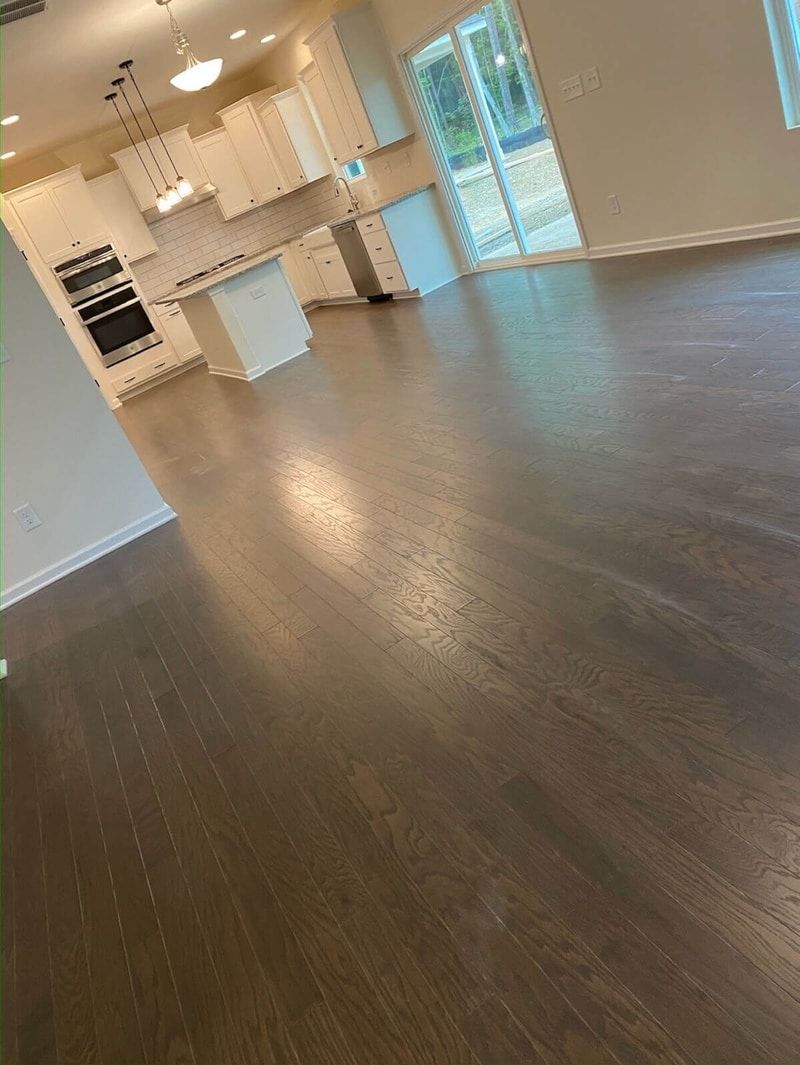 Dark wood floor in a brightly lit room with white cabinets and appliances.