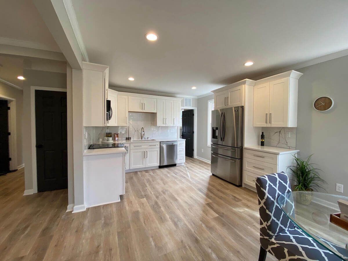 Modern kitchen with white cabinets, stainless steel appliances, and wood-look flooring.