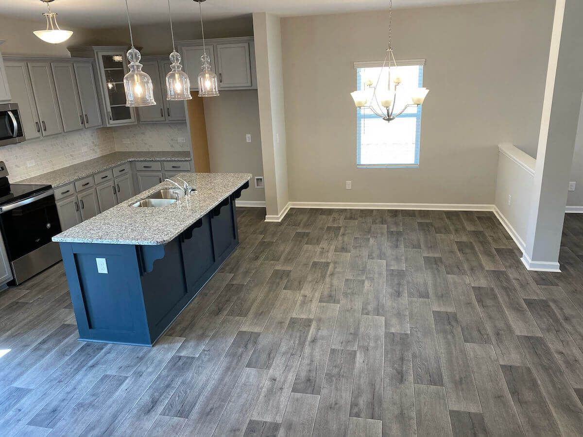 Kitchen and dining area with gray cabinets, island, and wood-look flooring.