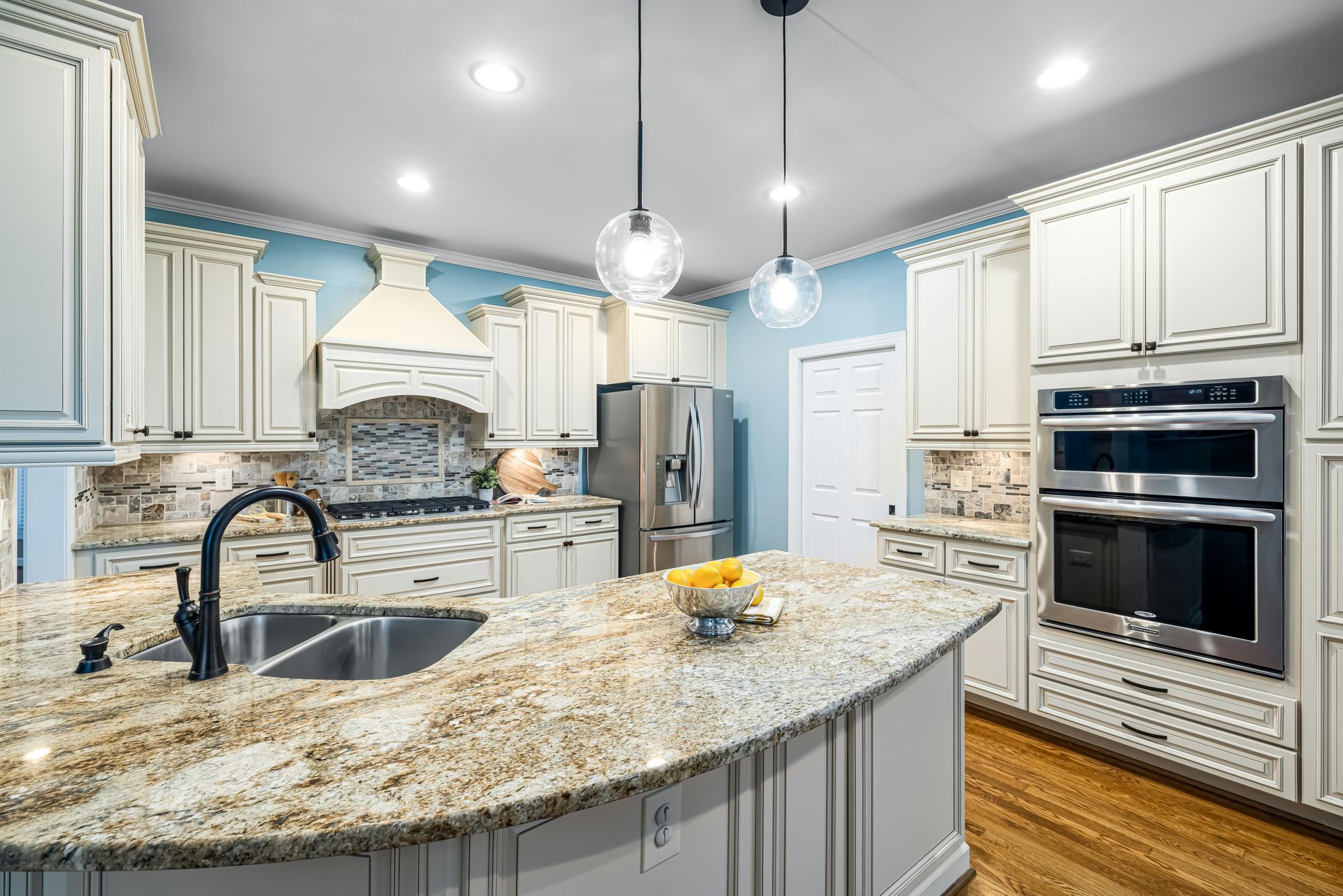 White kitchen with island, seating, and overhead lights. Dining table with window view.
