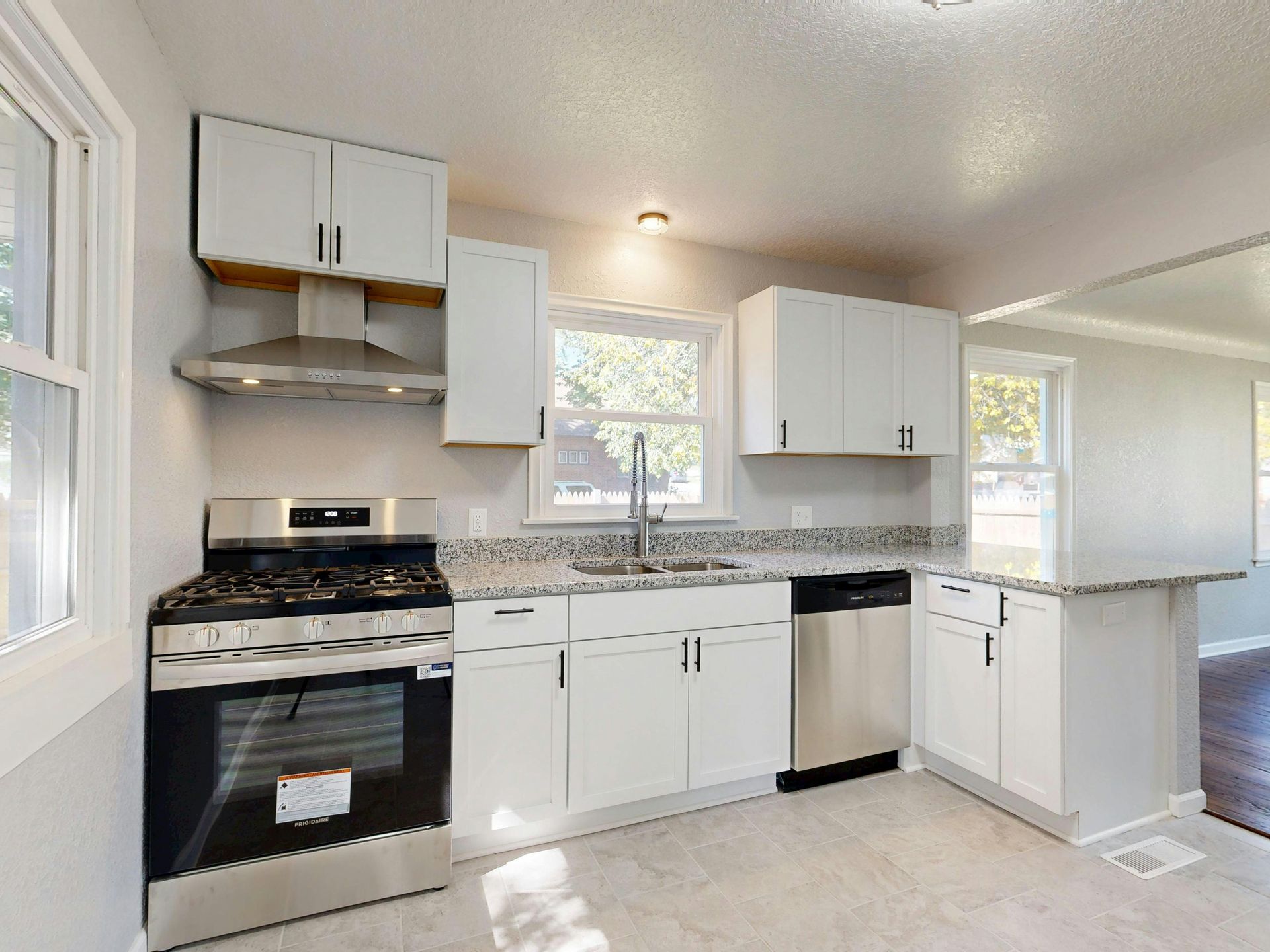 Modern kitchen with white cabinets, stainless steel appliances, and a granite countertop.