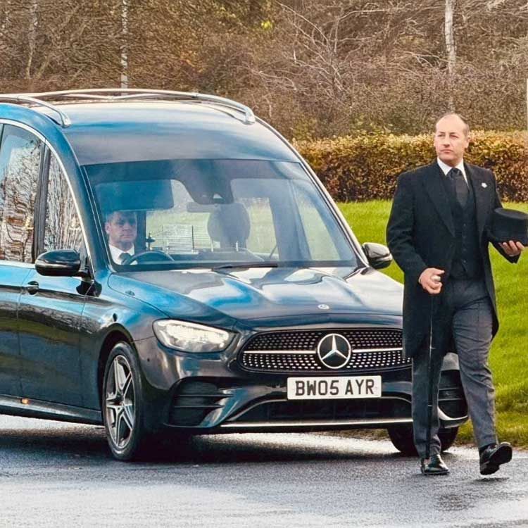 Barry  Whalen walking in front of the funeral car