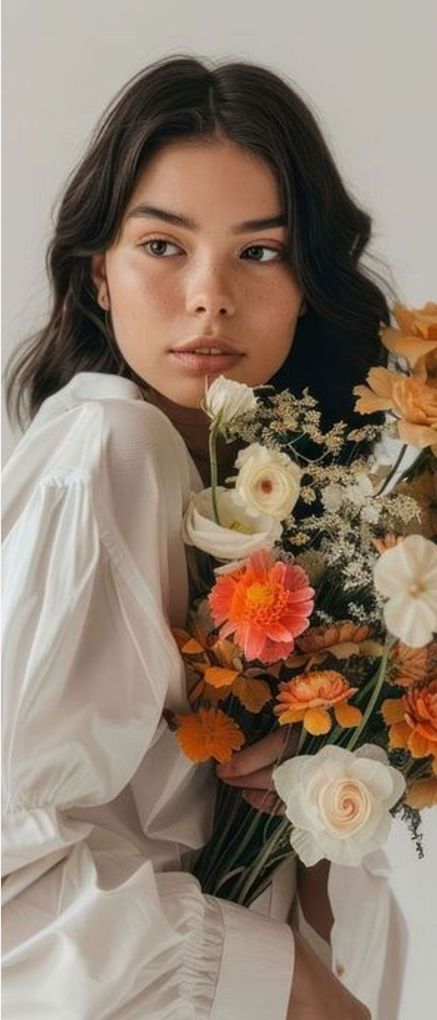 A woman in a white shirt is holding a bouquet of flowers.
