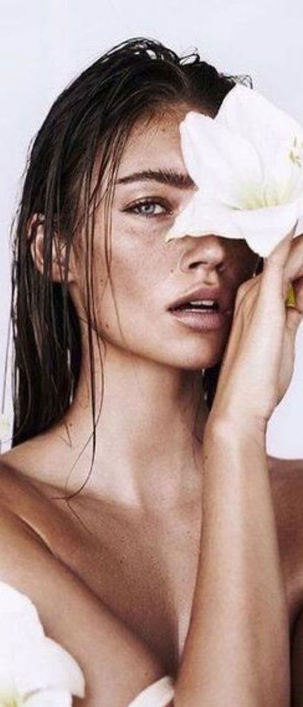 A woman is covering her face with a white flower.