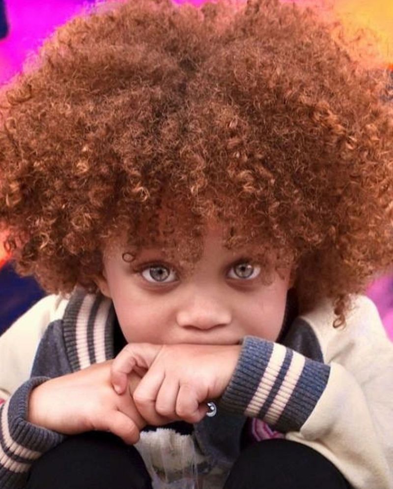 A little boy with a big afro and blue eyes