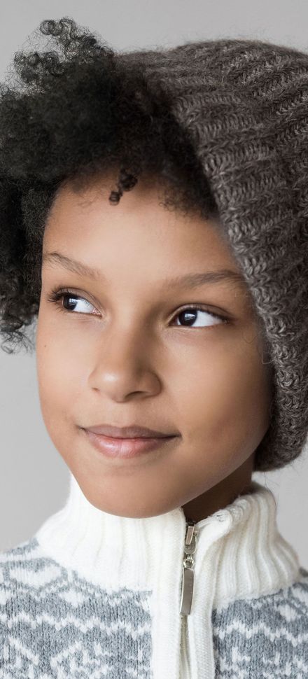 A close up of a young boy wearing a hat and sweater.