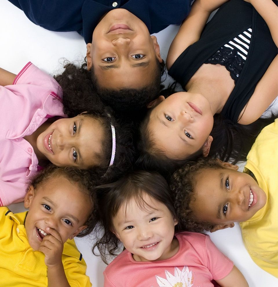 A group of children are laying in a circle and smiling
