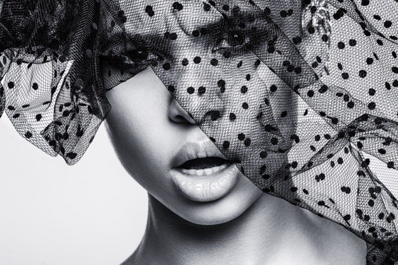 A black and white photo of a woman wearing a veil over her face.
