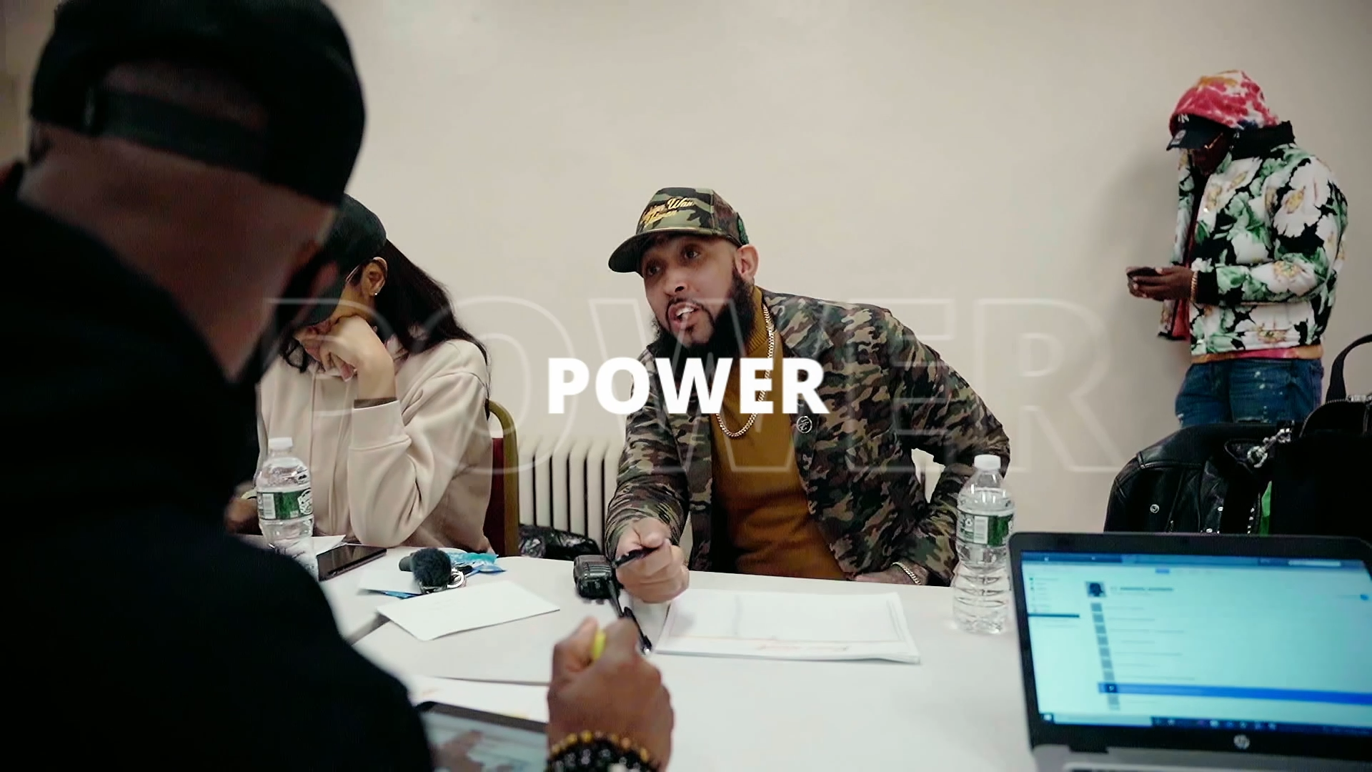 A group of people are sitting around a table with a laptop.