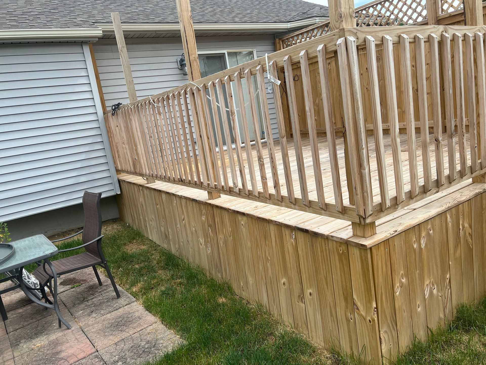 A wooden deck with a table and chairs in front of a house.