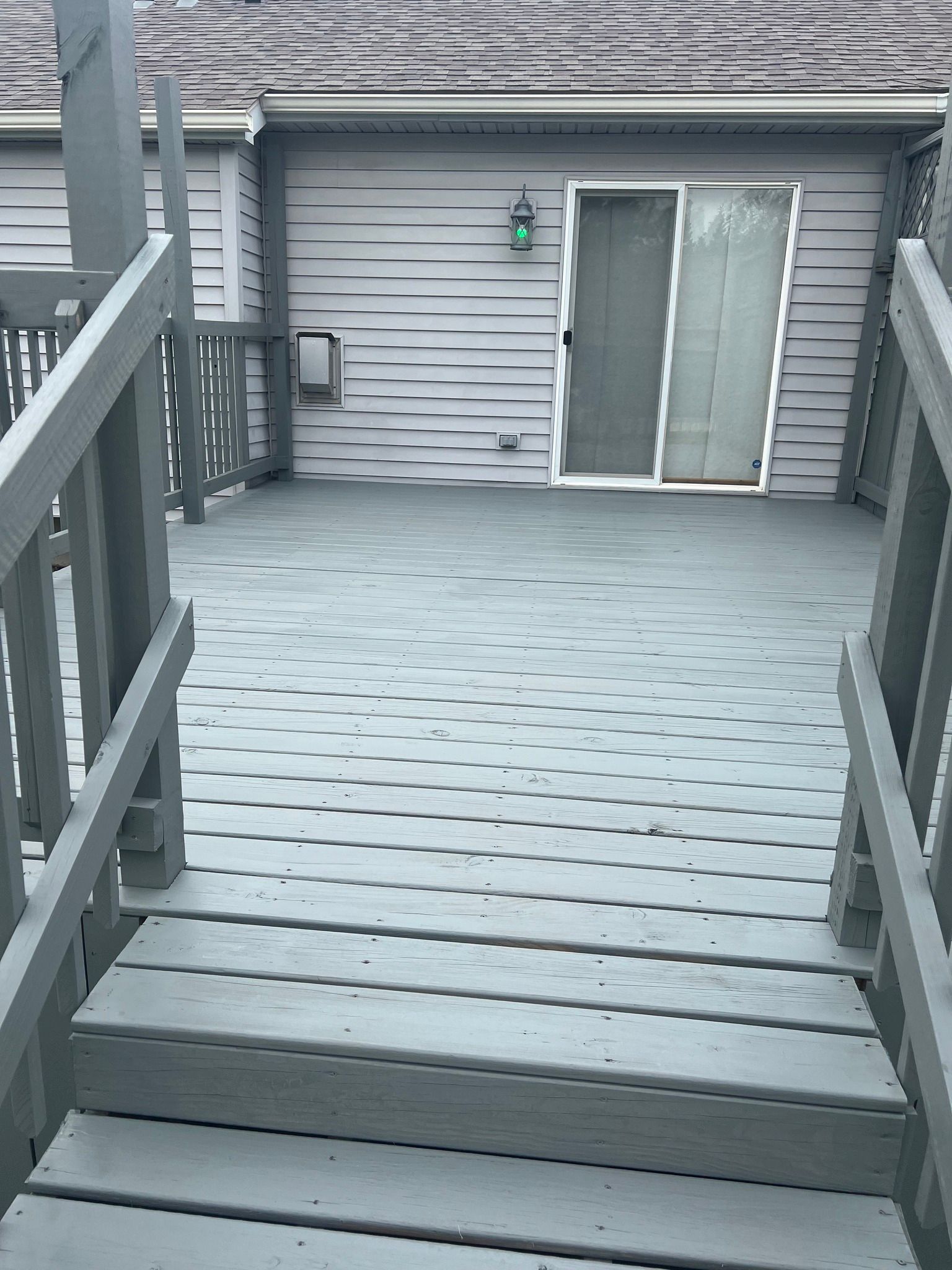 A wooden deck with stairs leading up to it and a sliding glass door.