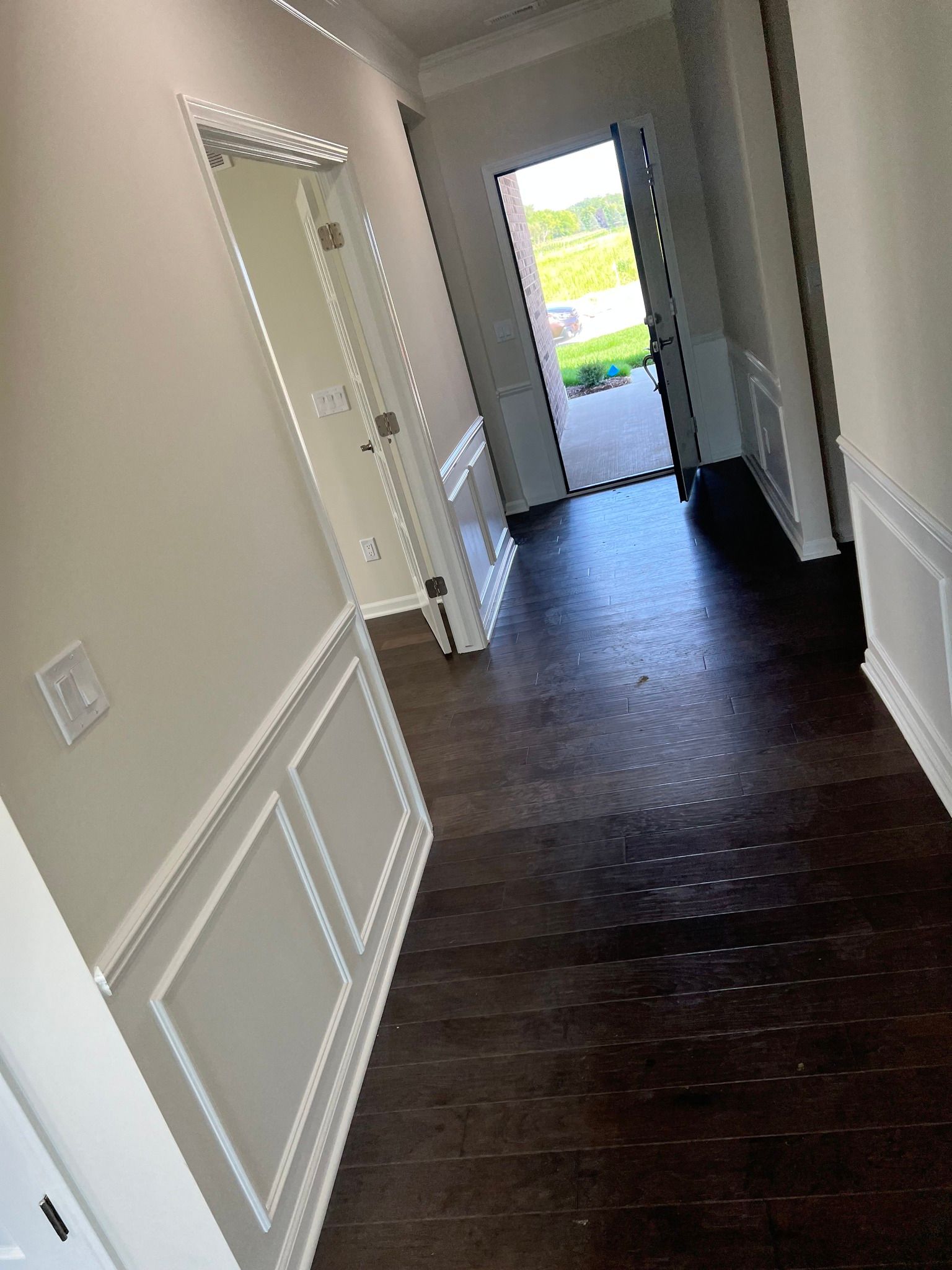 A hallway in a house with hardwood floors and white trim.
