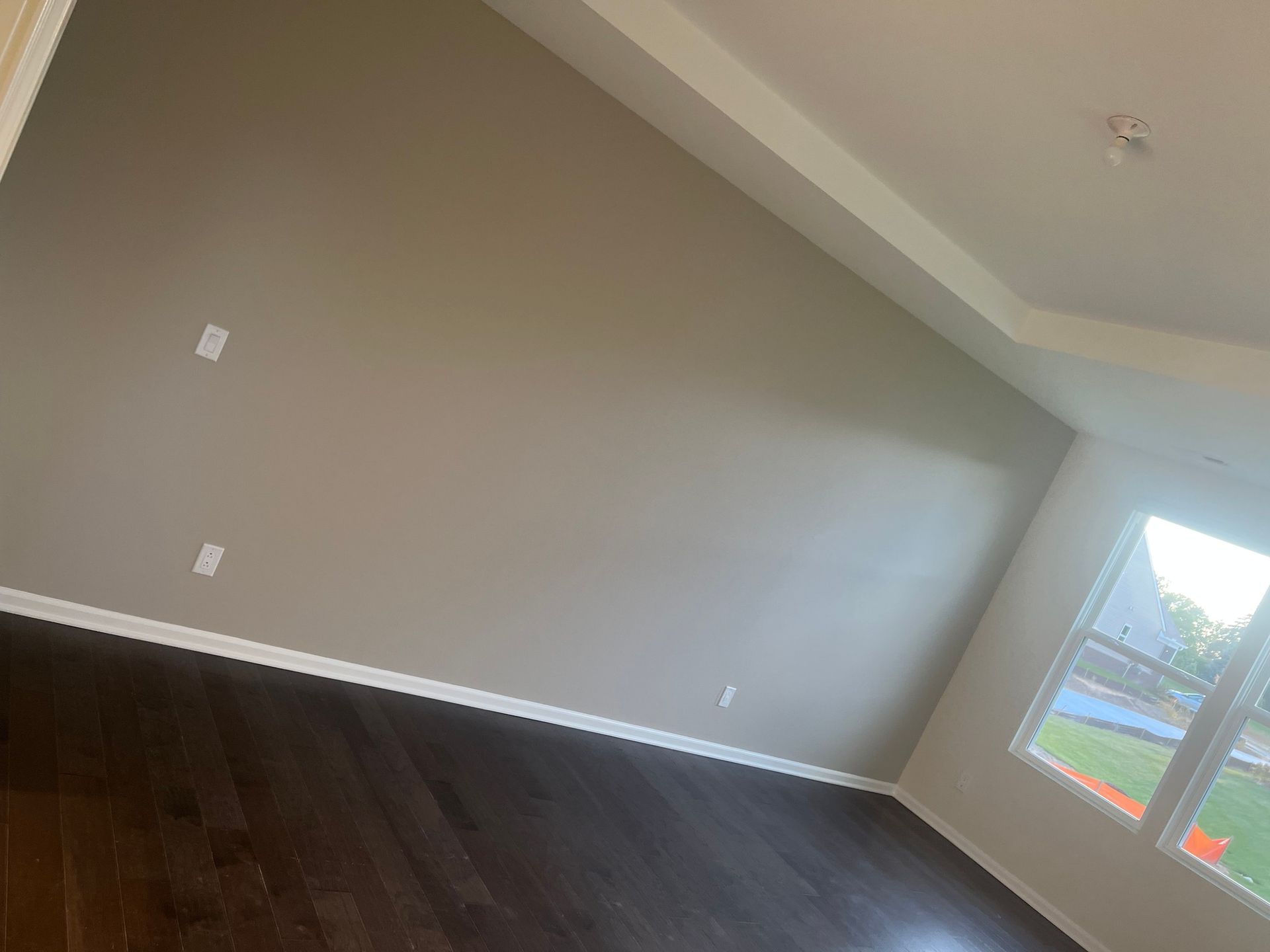 An empty room with a hardwood floor and a window.