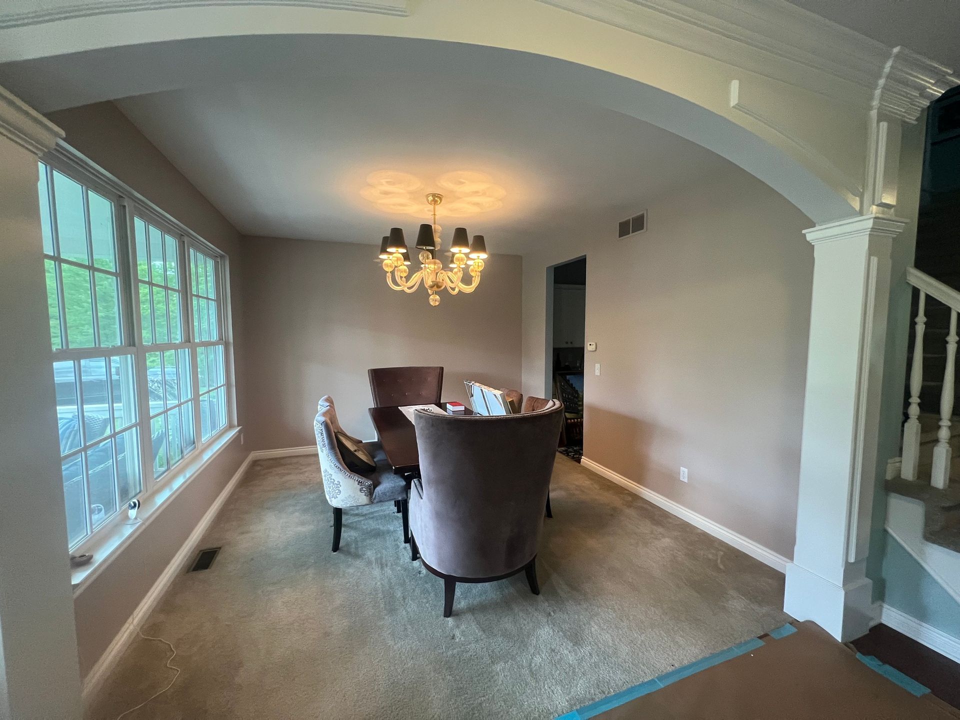 A dining room with a table and chairs and a chandelier hanging from the ceiling.