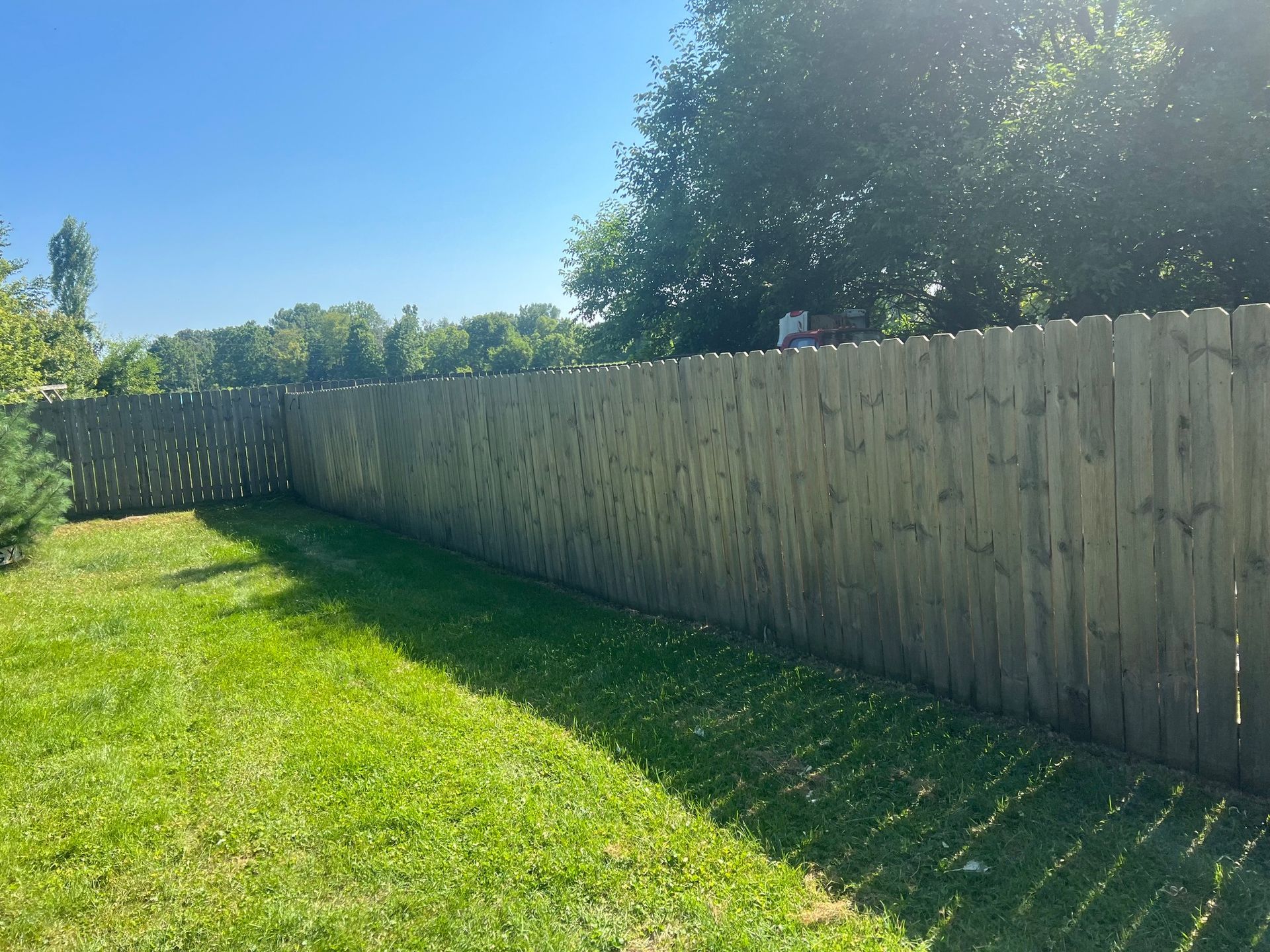 A wooden fence surrounds a lush green yard.