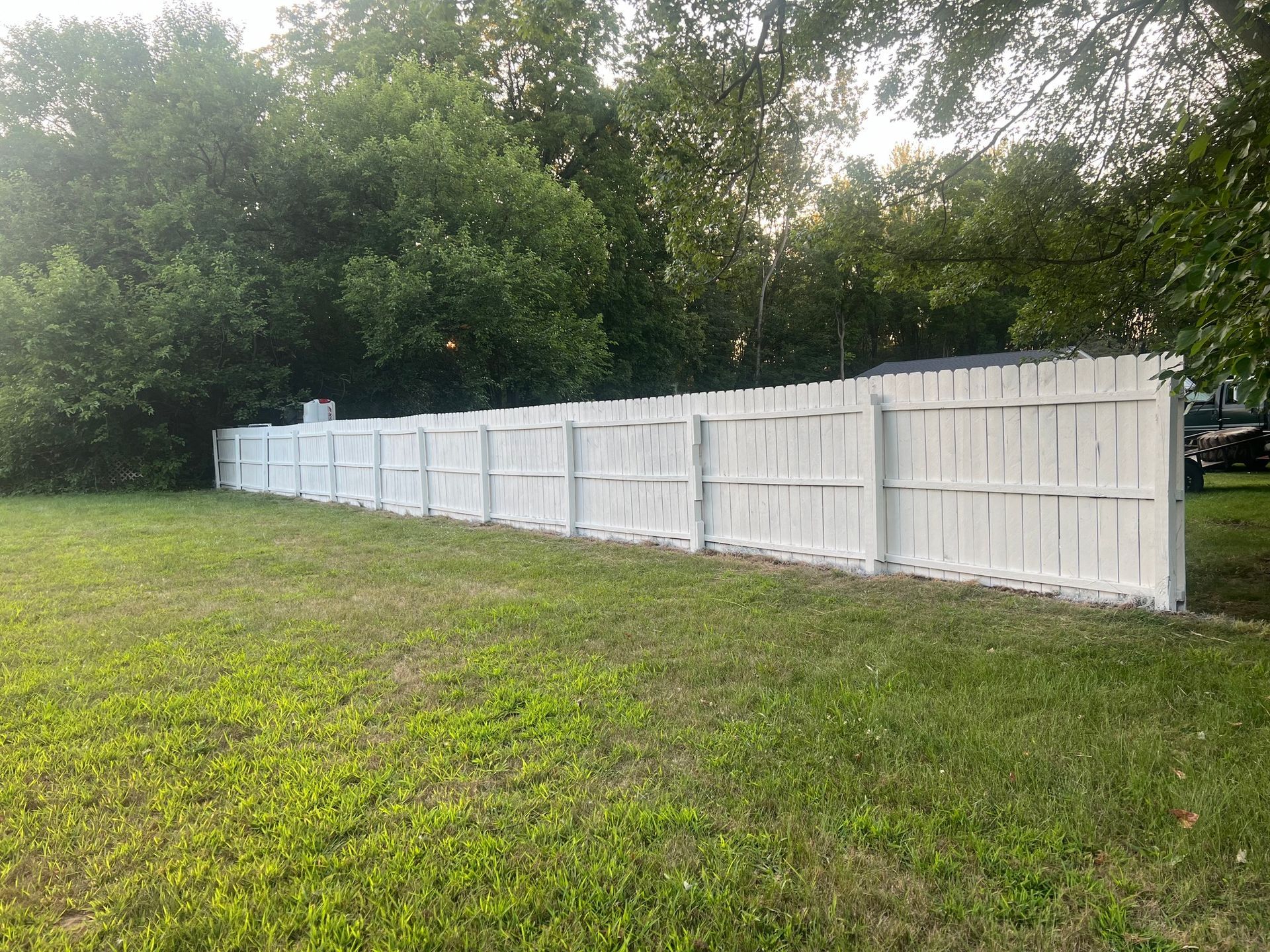 A long white fence is sitting in the middle of a lush green field.
