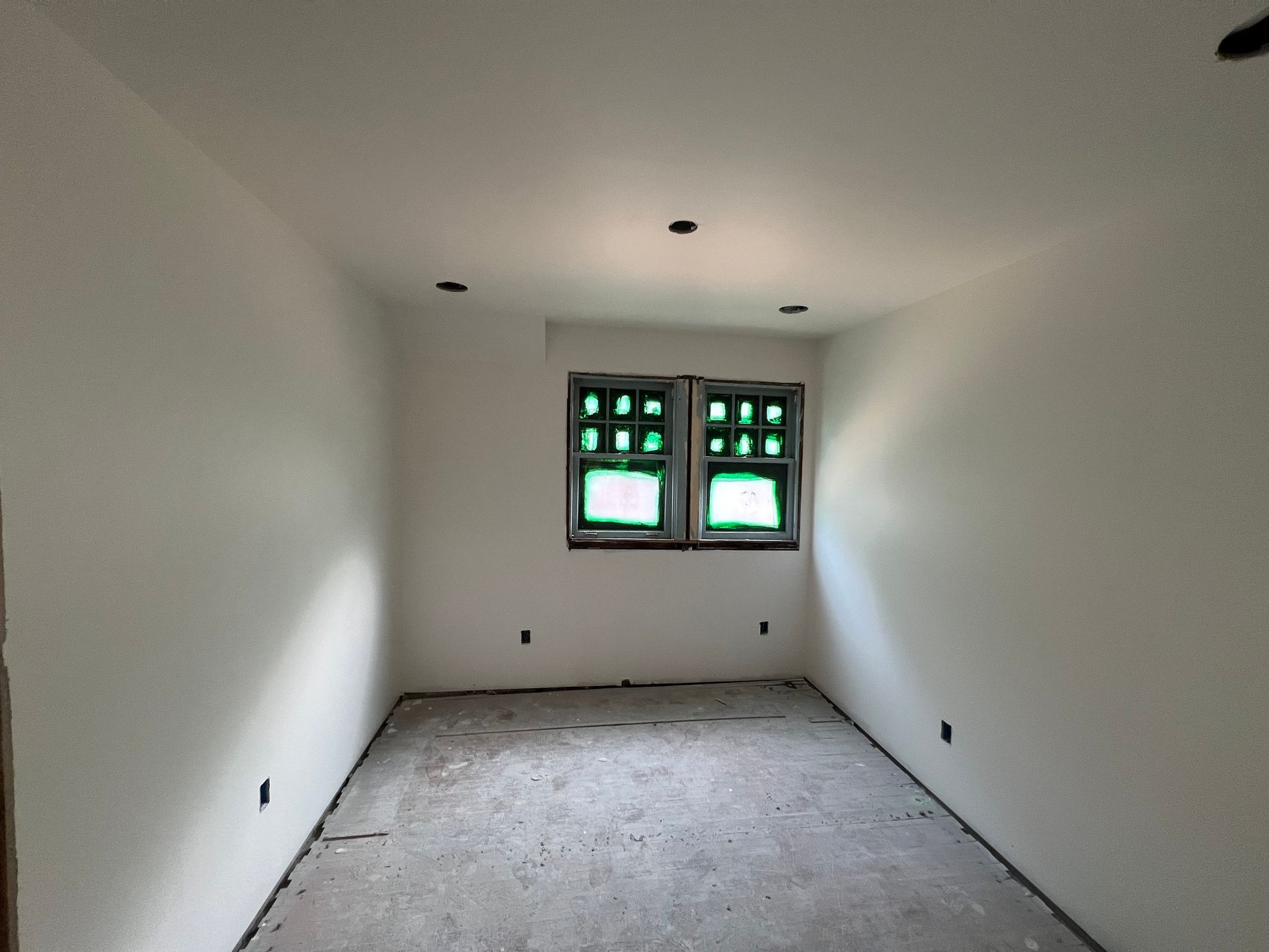 A room with white walls and two green windows