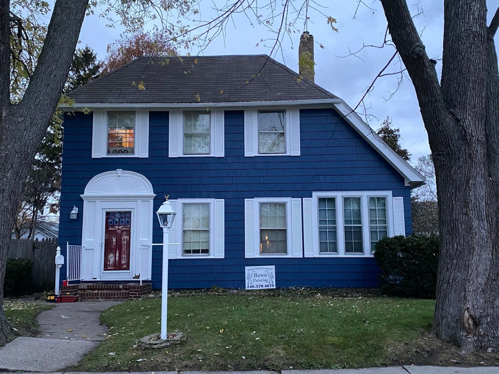 A blue house with white shutters and a red door