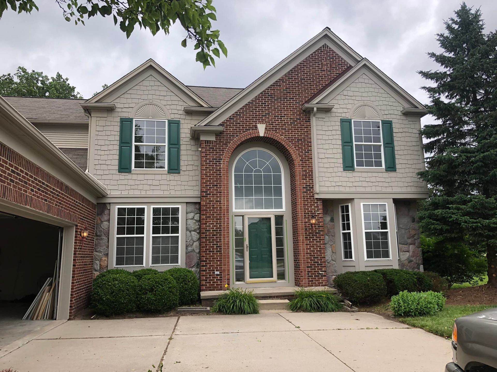 A large brick house with green shutters and a car parked in front of it