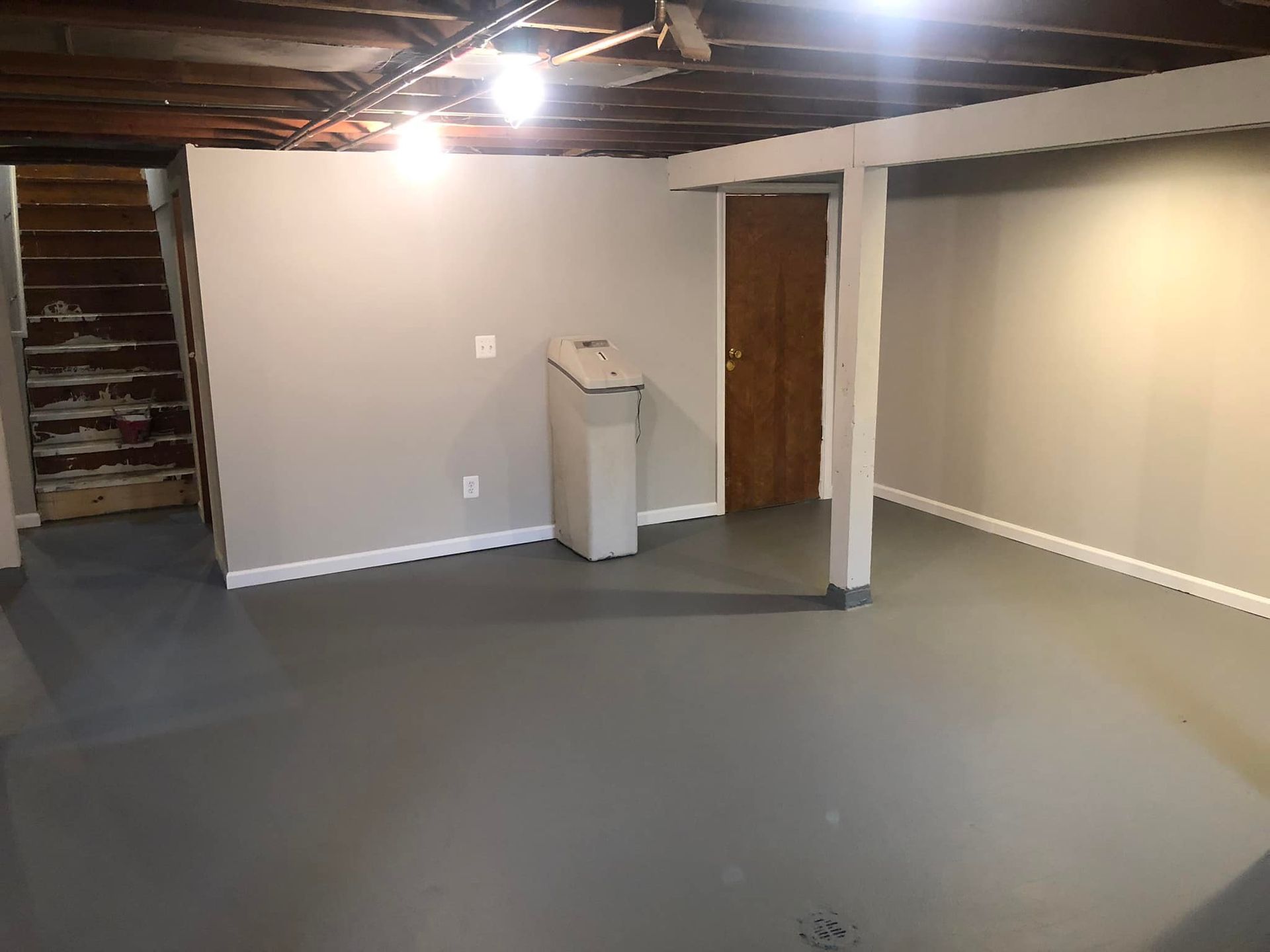 There is a trash can in the middle of the room in the basement.