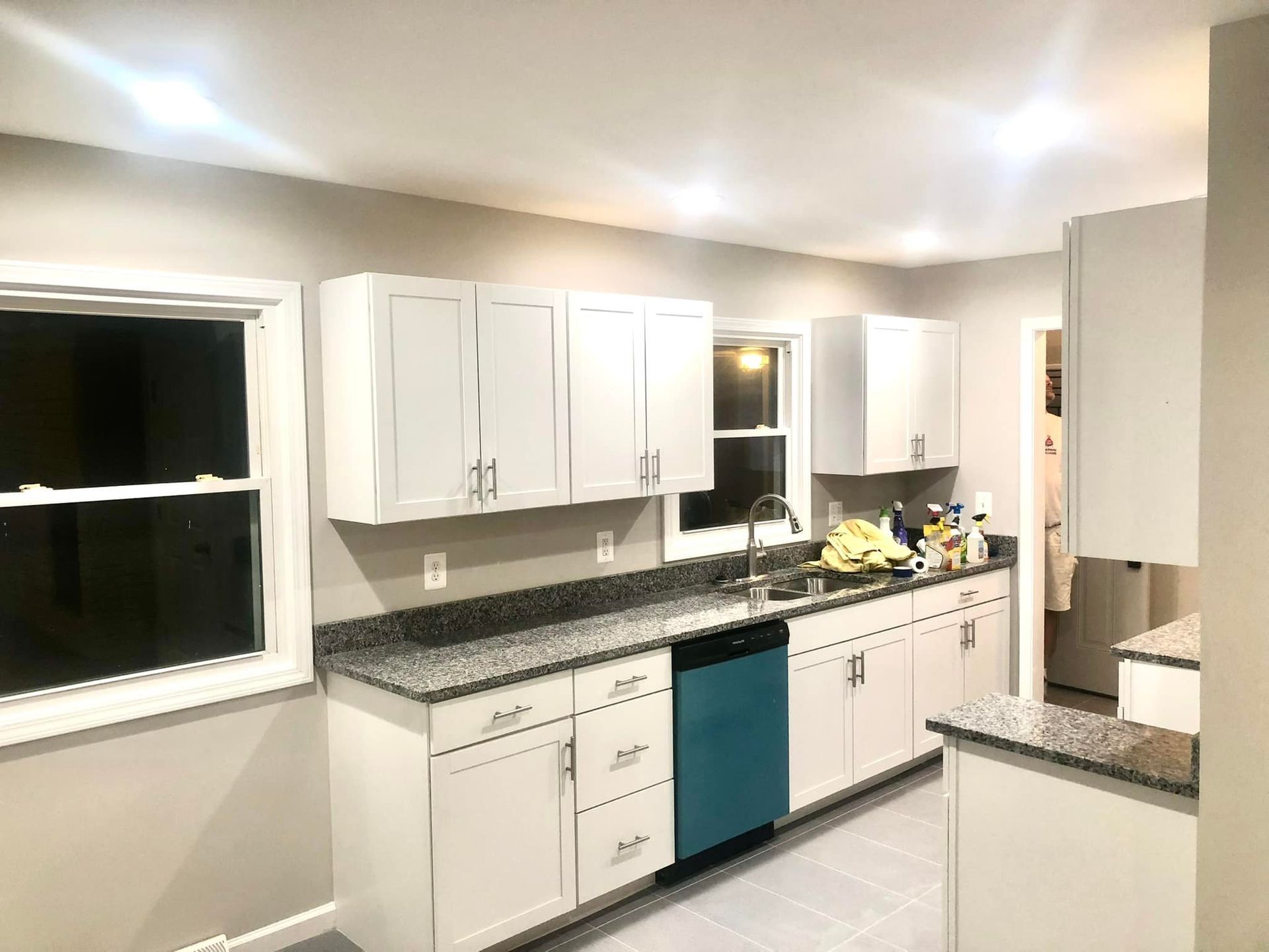 A kitchen with white cabinets and a blue dishwasher