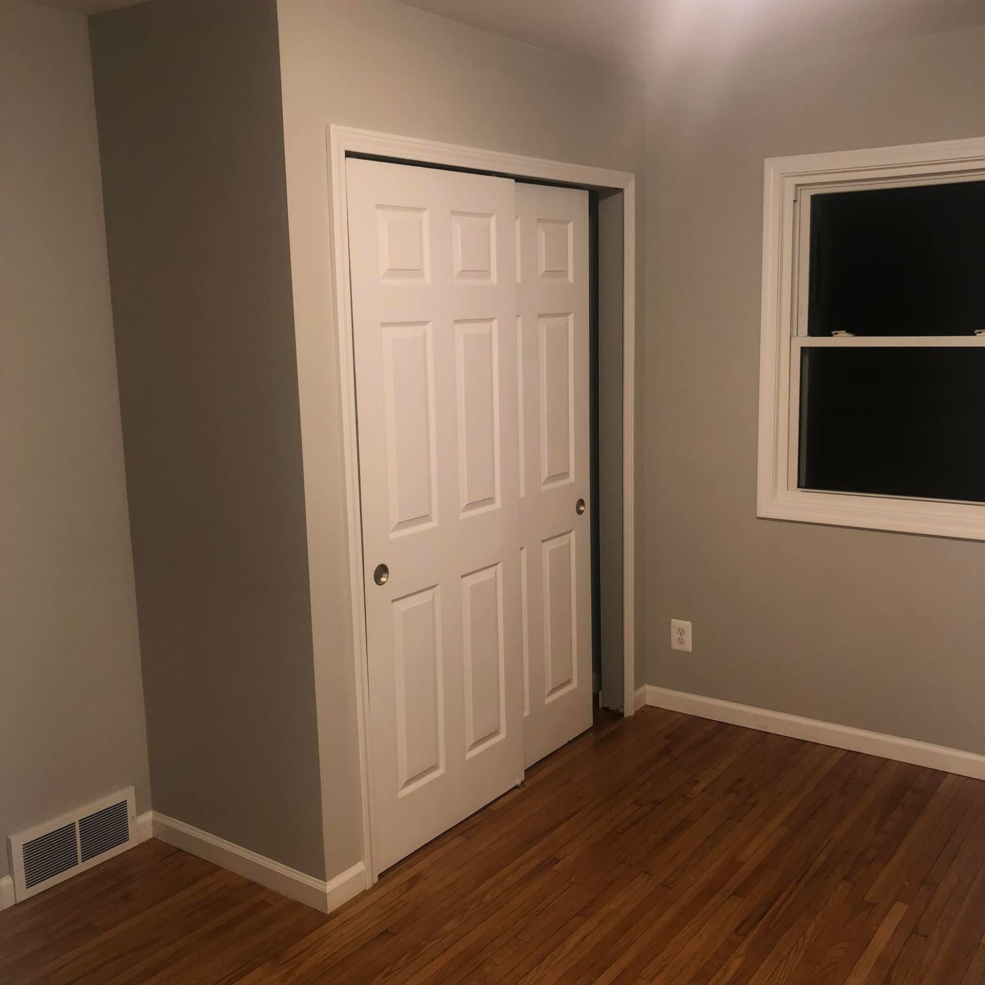 An empty room with a closet and a window.
