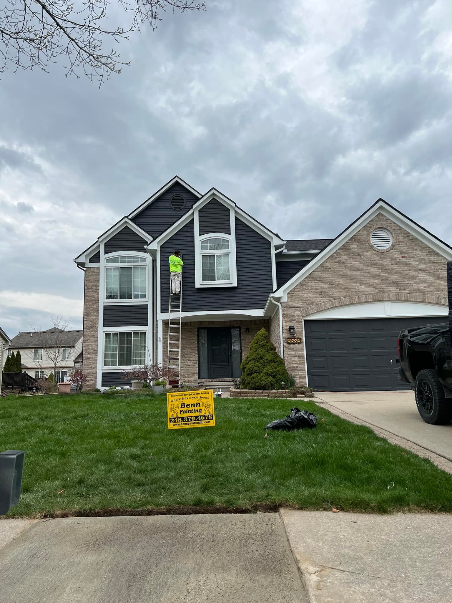 A house is being painted black with a yellow sign in front of it.