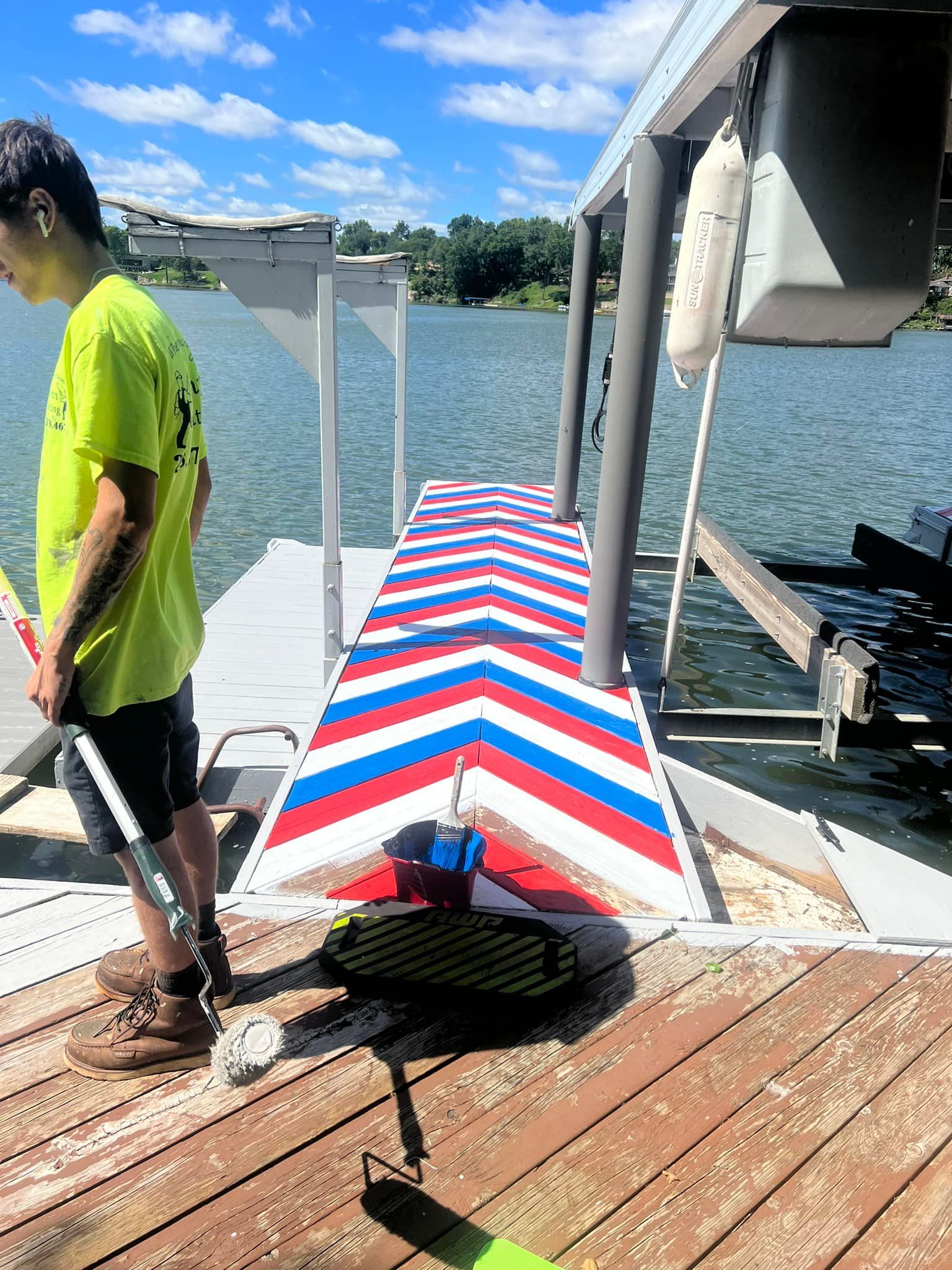 A boy in a yellow shirt is standing on a dock near a lake.