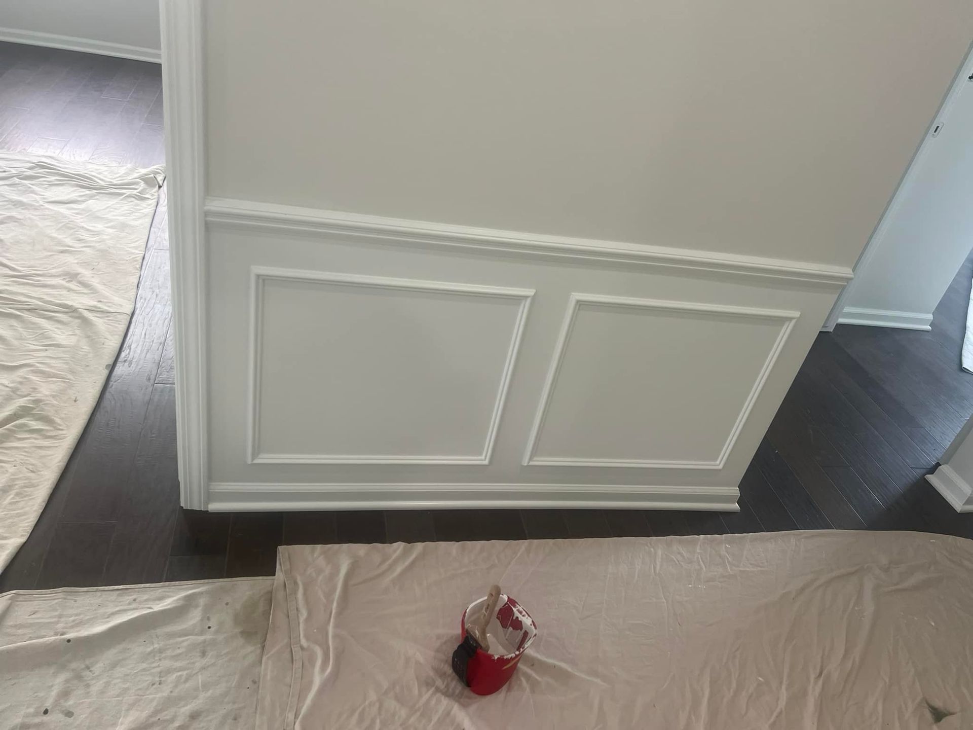 A bucket of paint is sitting on a table next to a wall.