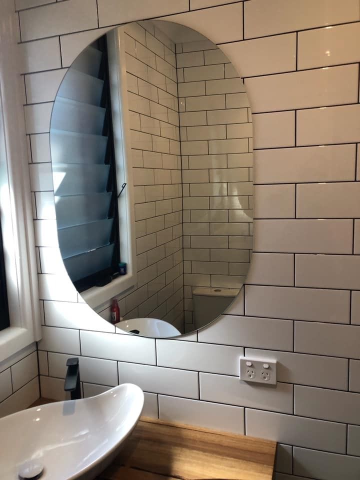 A Bathroom with White Tiles, a Sink and A Round Mirror — Gads Glass & Shower Screens in Albion Park, NSW