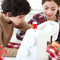 Two people focus intently while working together at a sewing machine with red and white checkered fabric.