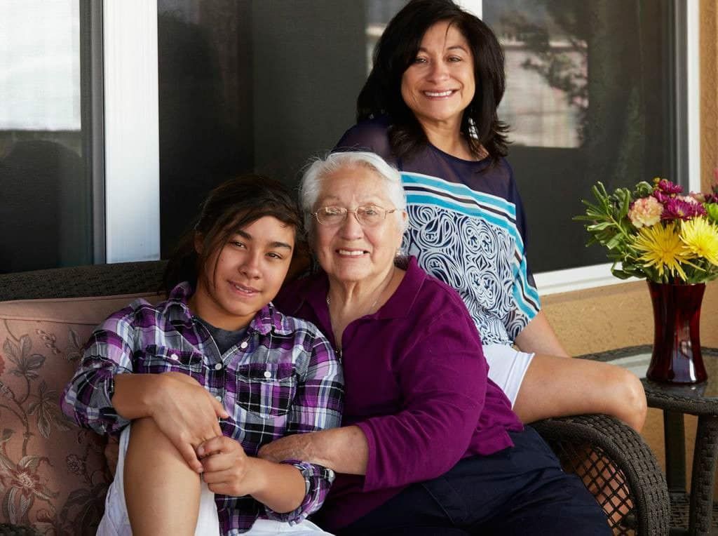 Three women are posing for a picture while sitting on a couch.