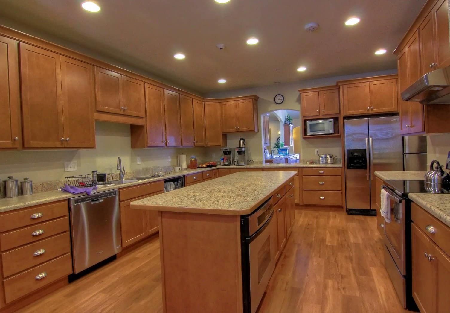 A kitchen with wooden cabinets , granite counter tops , stainless steel appliances and a large island.