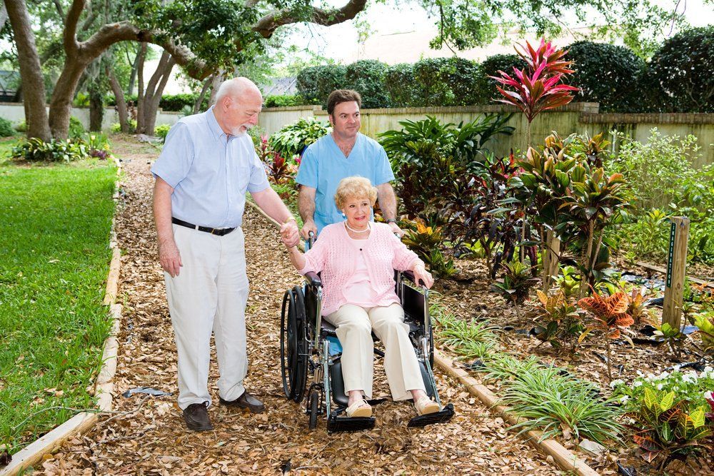 A woman wearing a mask is standing in front of a group of elderly people.