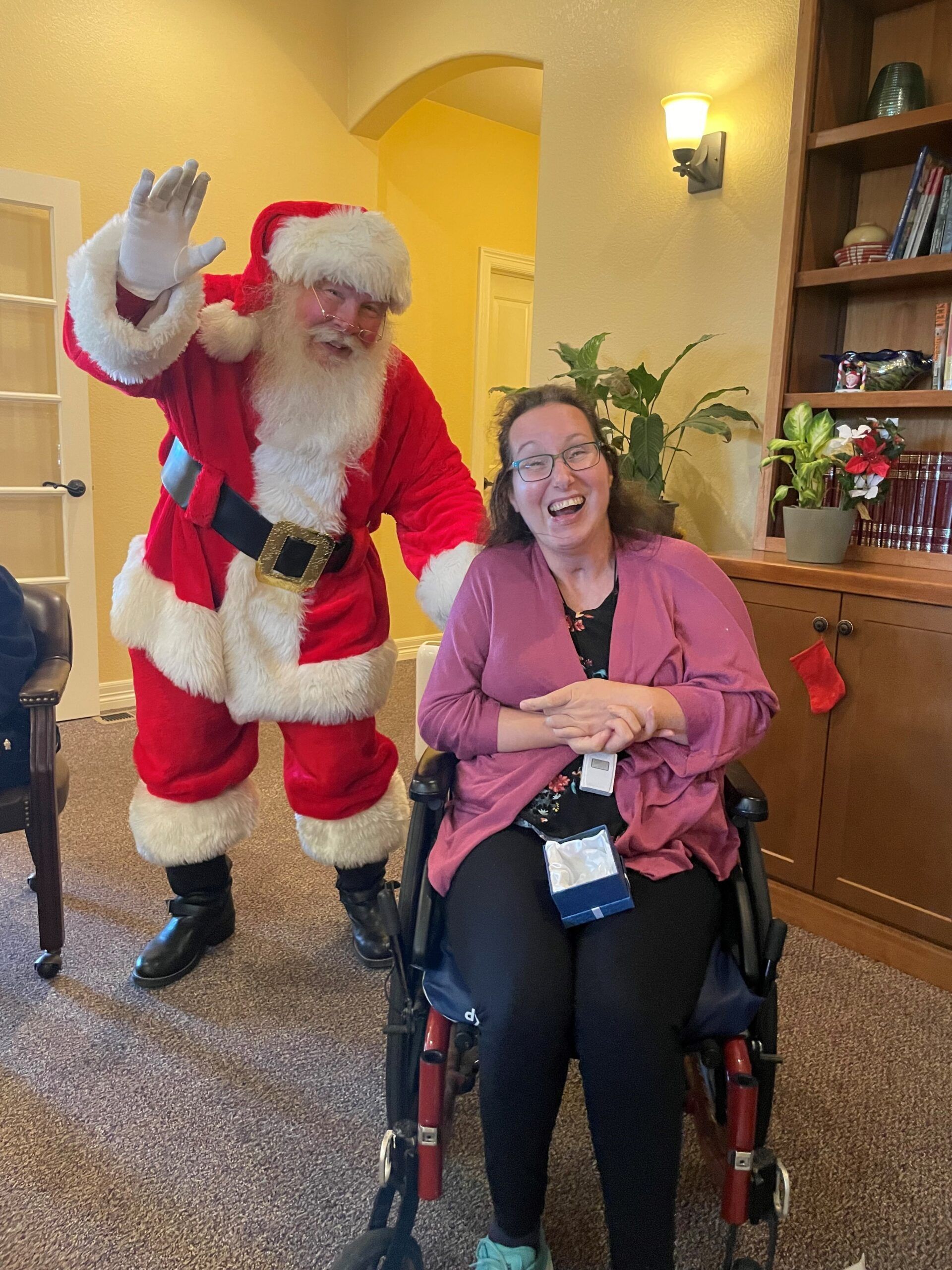 A woman in a wheelchair is posing for a picture with santa claus.