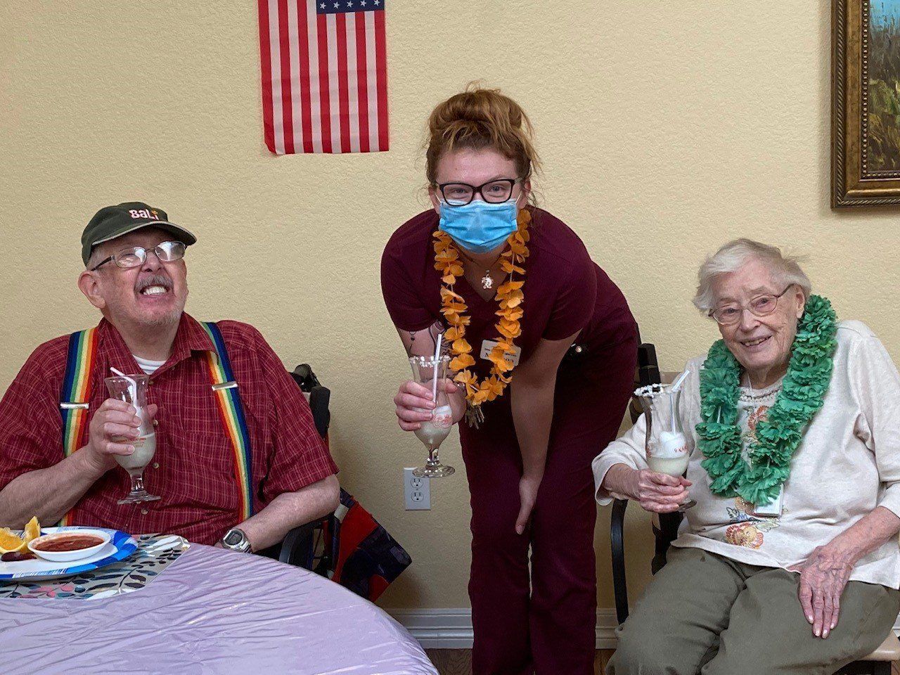 A woman wearing a mask is standing next to two elderly people holding wine glasses.