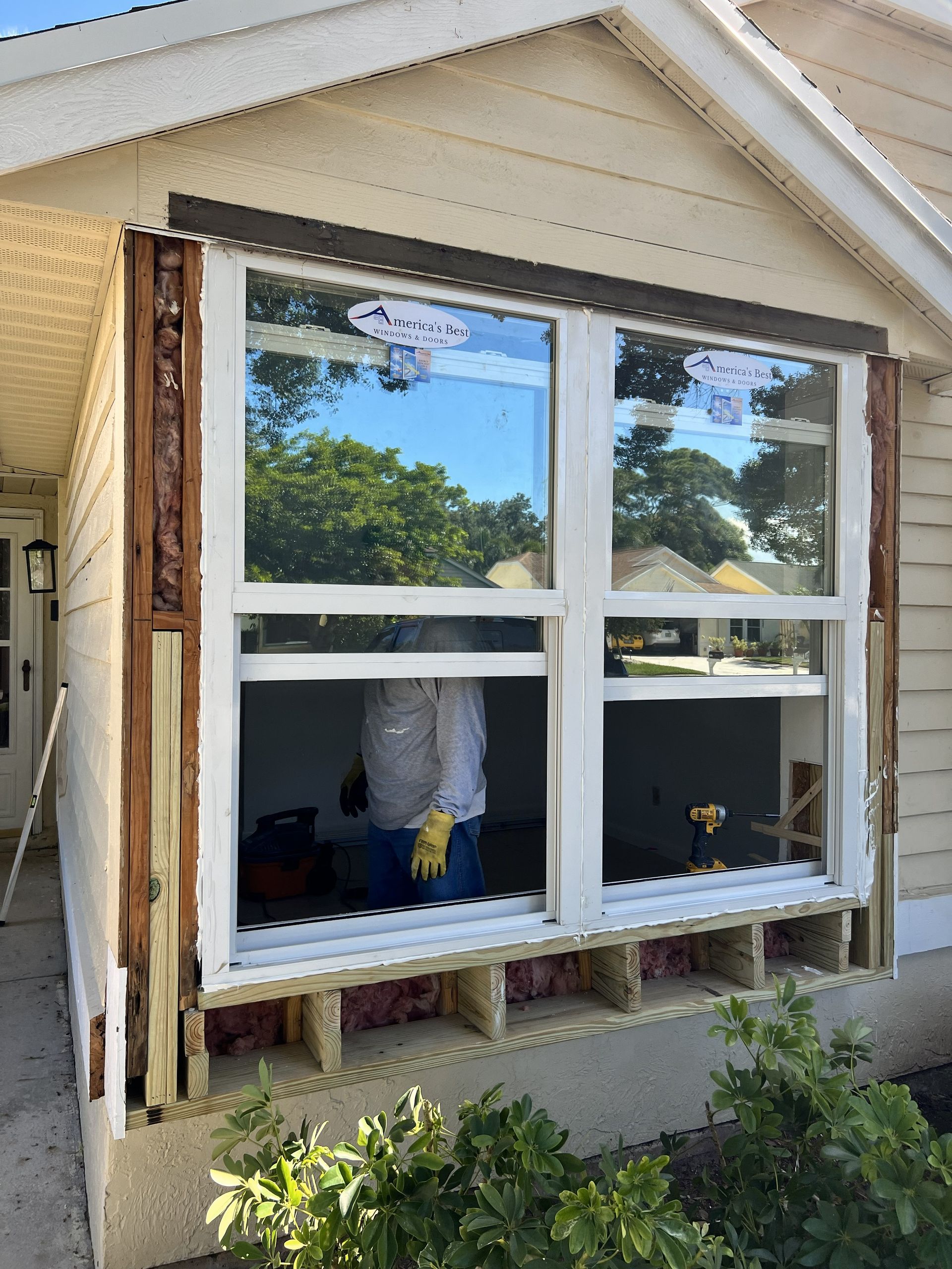 Installation of new windows, exterior view. A person in yellow gloves works at the construction site.