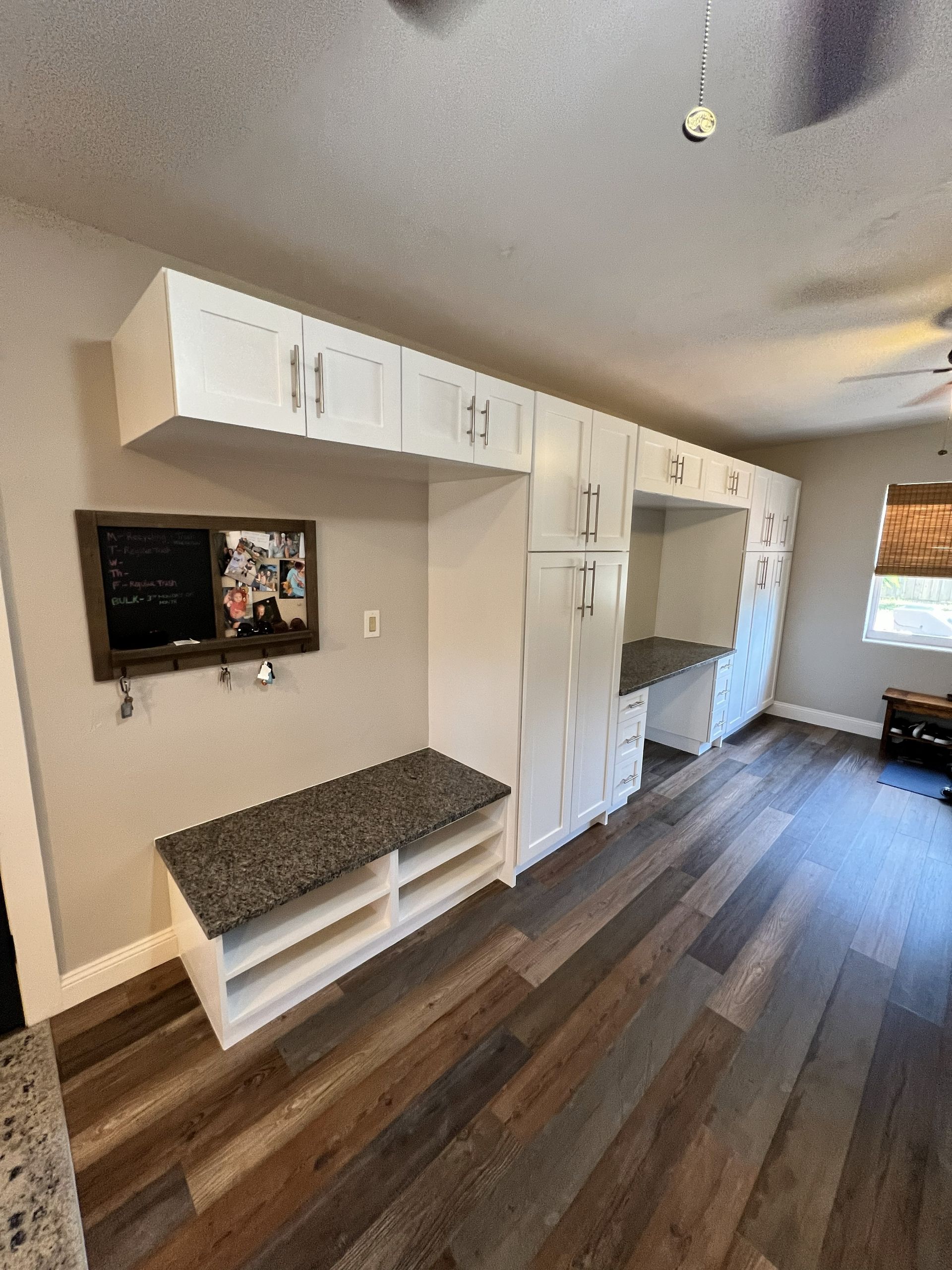 Built-in white storage cabinets with desk and bench, set against light-colored walls and wood flooring.